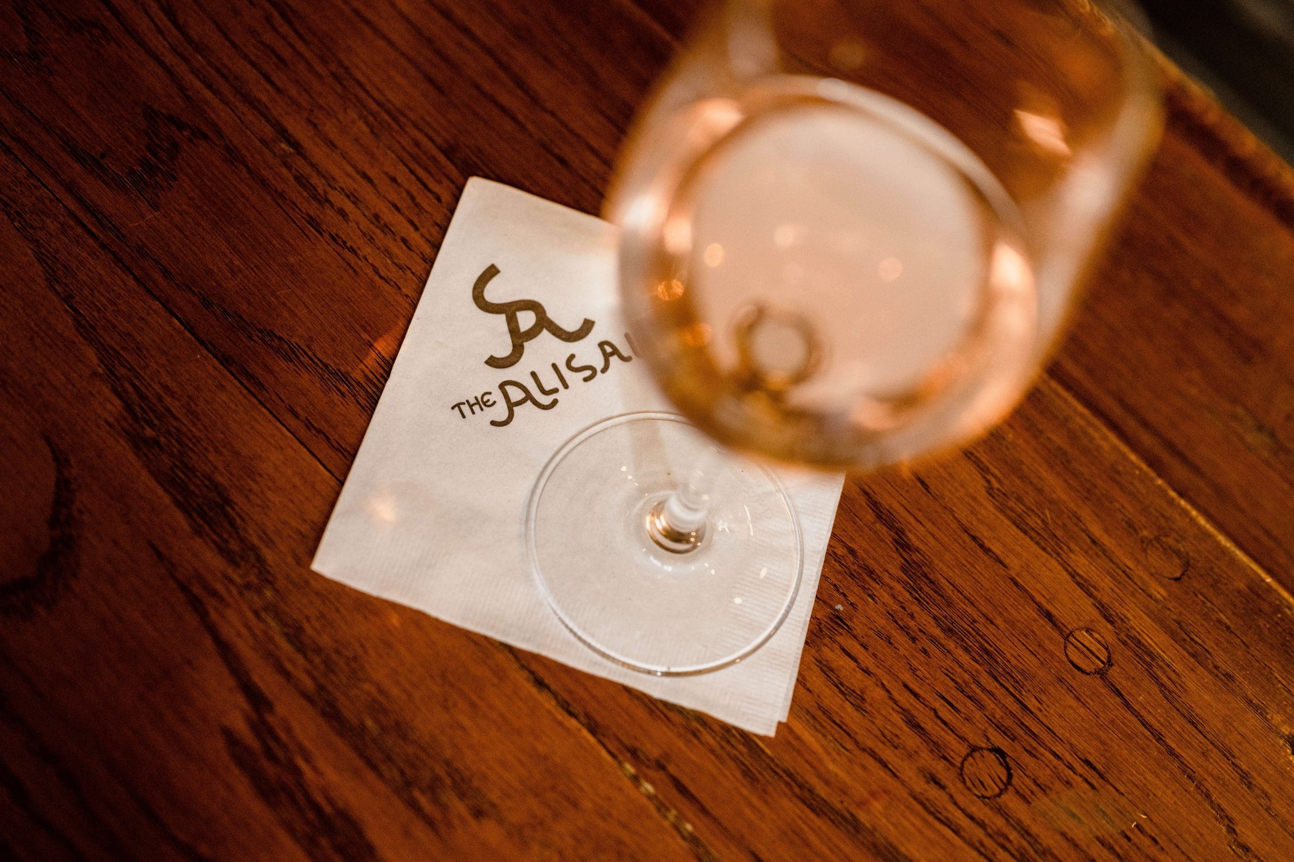 glass of alisal wine on top of a napkin on a wooden table