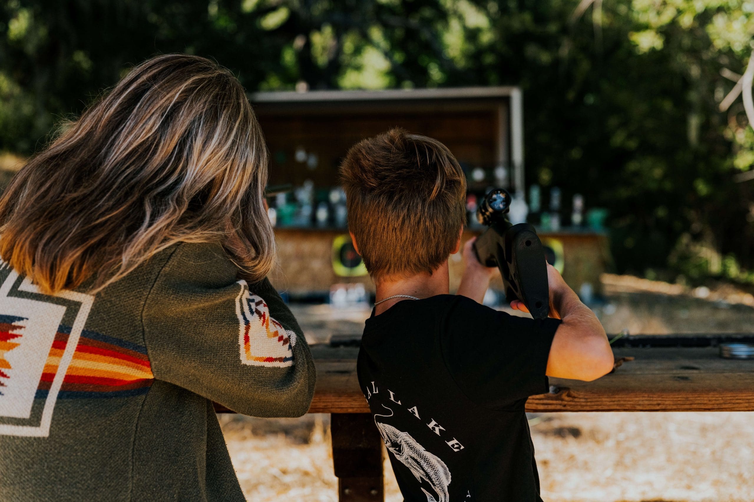 adult and young person pointing air rifles at targets