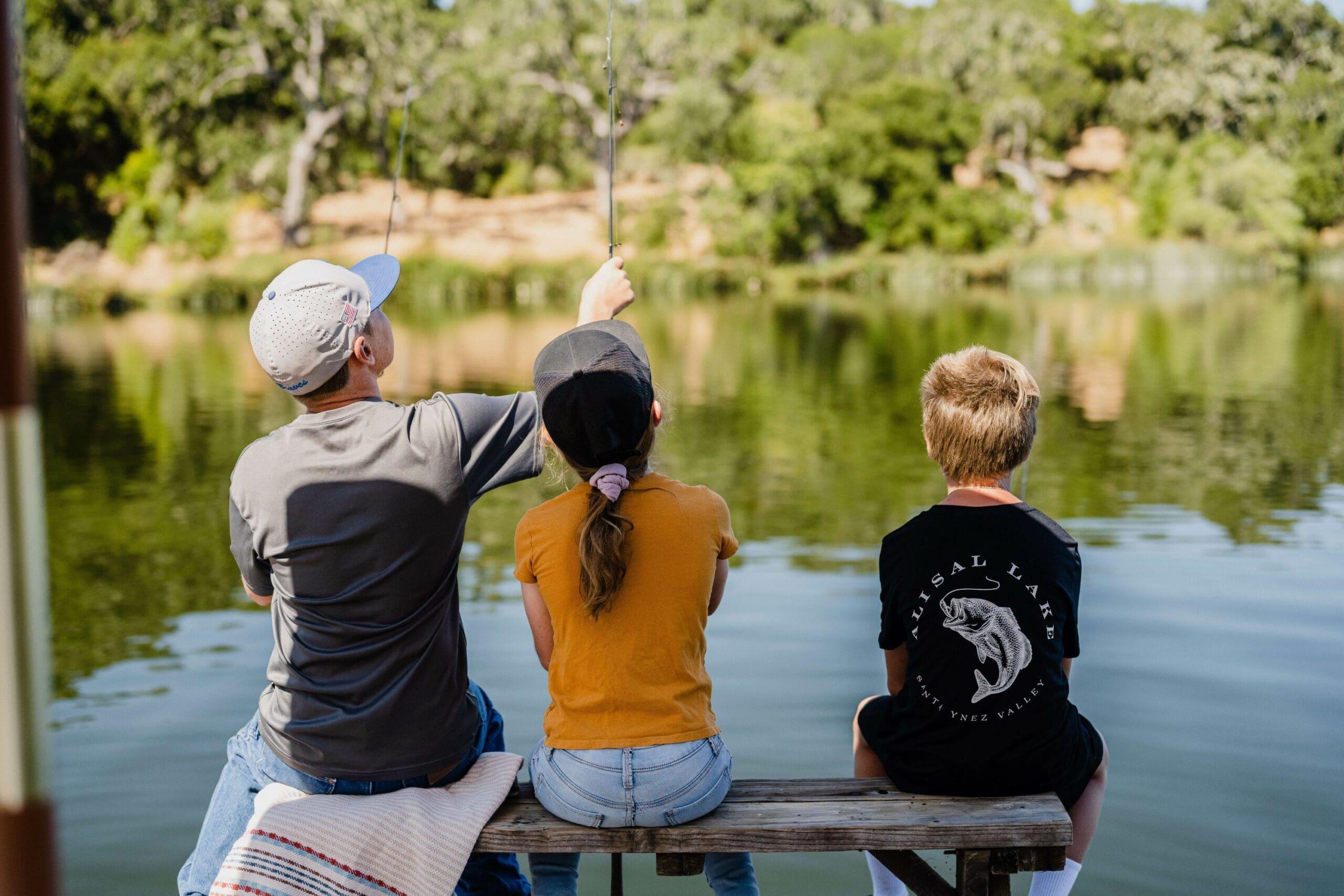 young people fly fishing from a bench