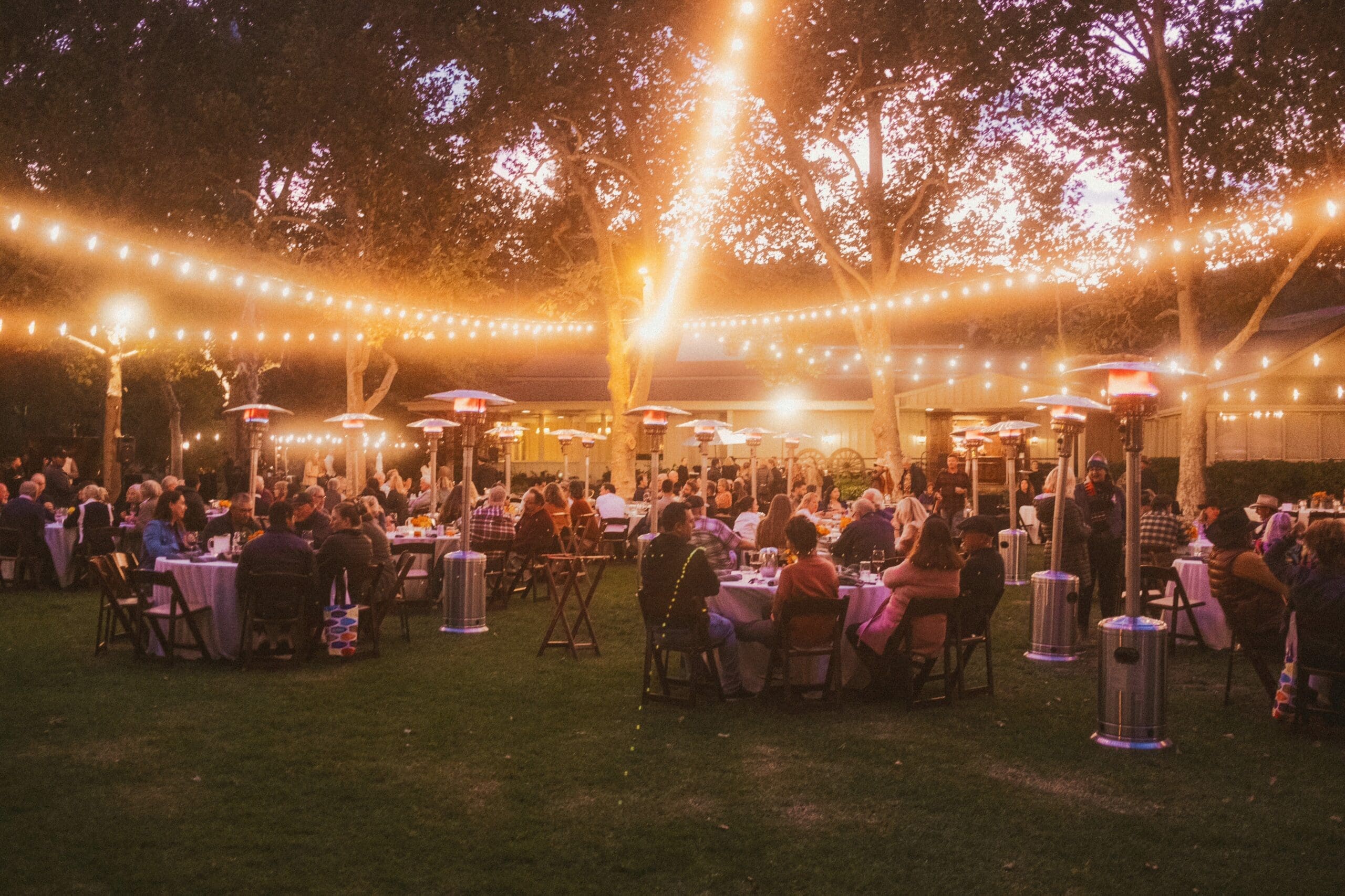 outdoor dining setup with hanging lights and heated lamps