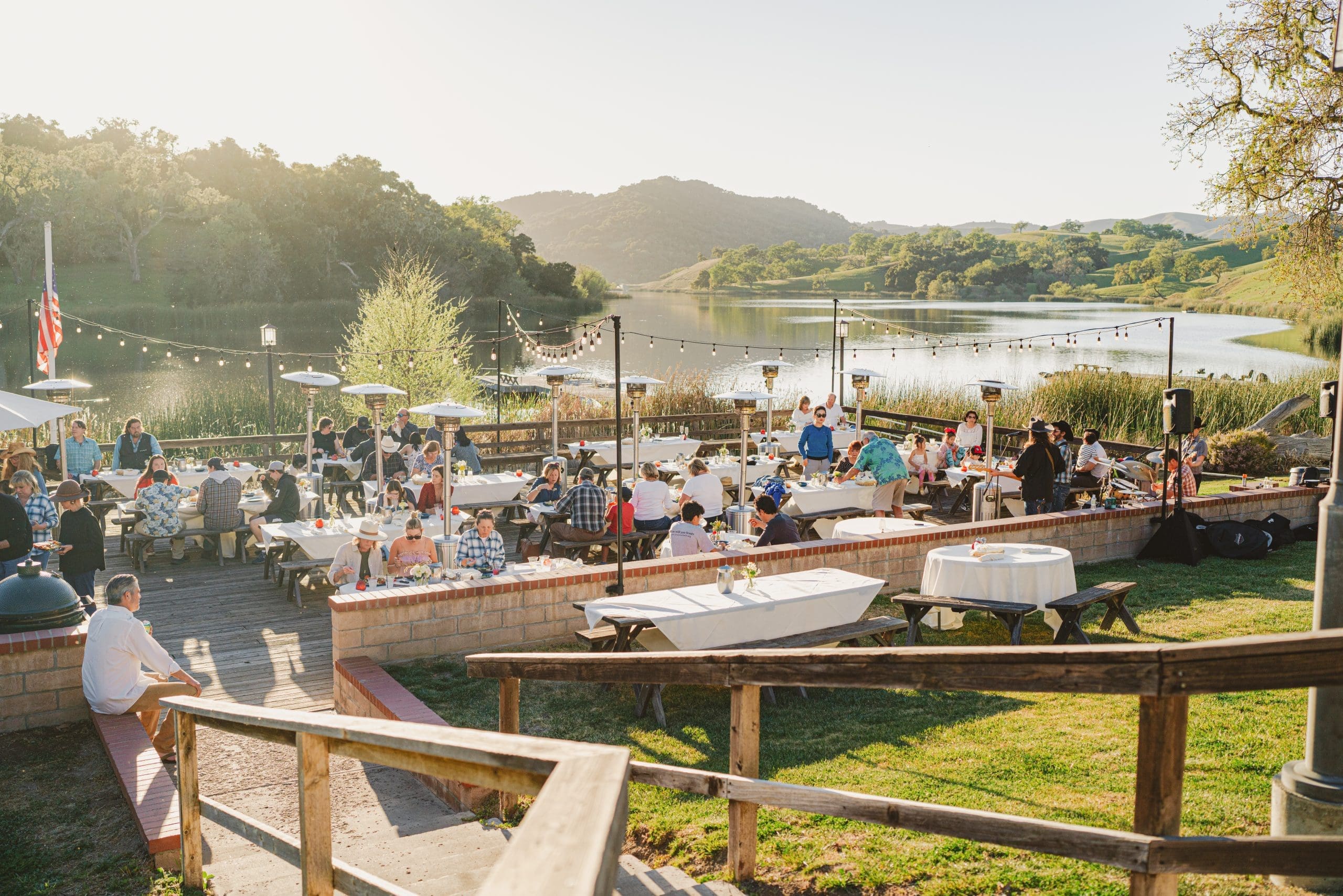 people eating at the outdoor dining area beside the lake