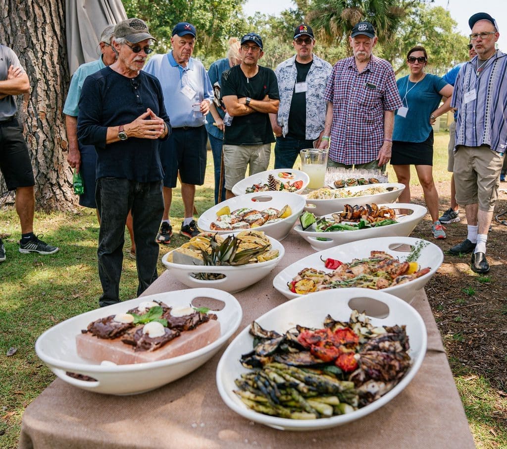 group of people standing around a table full of food