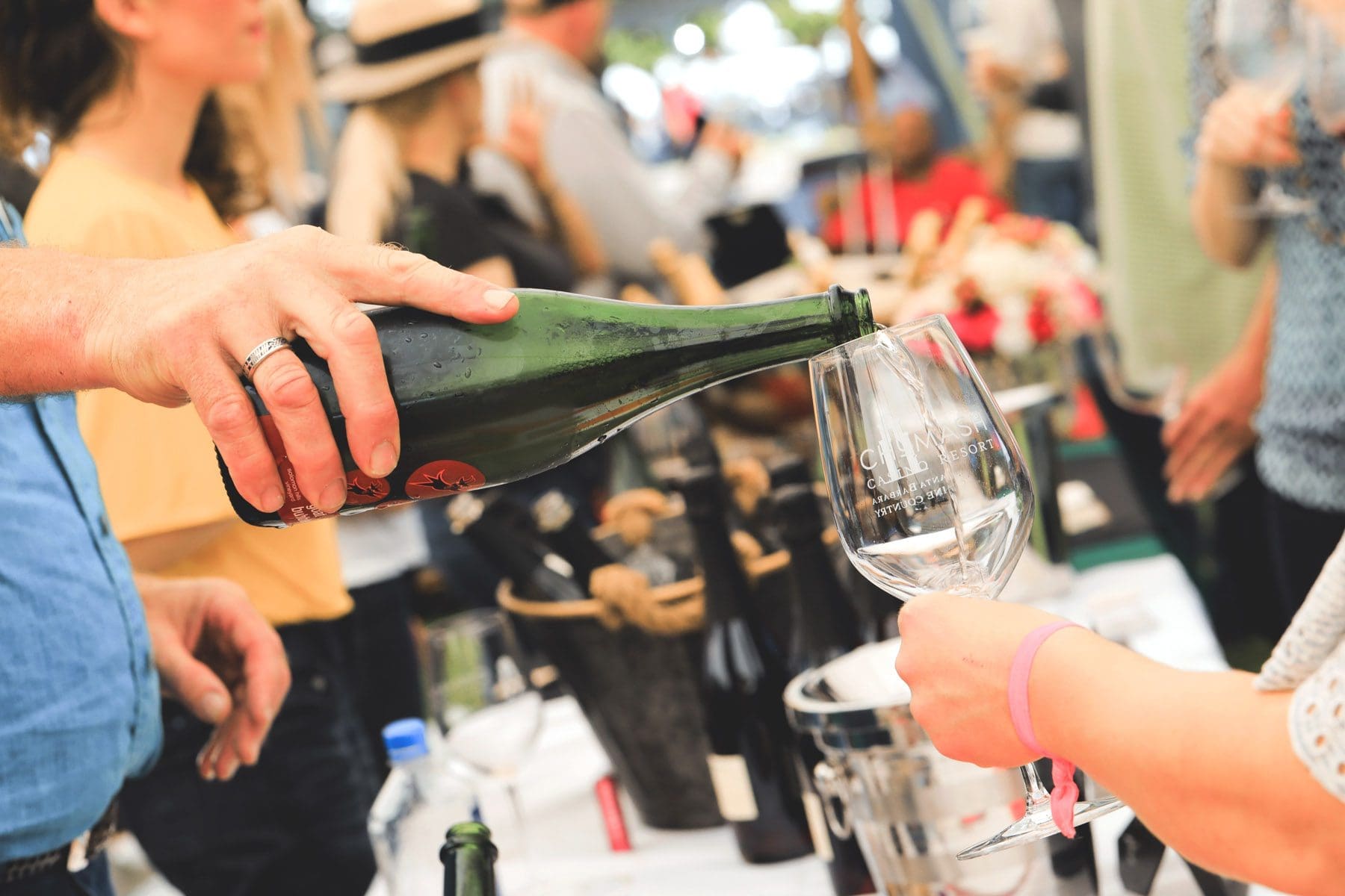 a person's right hand pulling a drink into a glass holding by another person's left hand